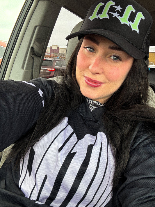 A person wearing a black trucker hat with the number 11:11 and a green graphic design on the front.Loveworldllc,Loveworldllc.com, mental health brand, mom brand, angel numbers,star hat, cool trucker hat,mother graphic tee, graphic designer, unique fashion, clothing brand, 1111,Pinterest outfit, self Love brand, mom brand,gifts for her, gifts for mom