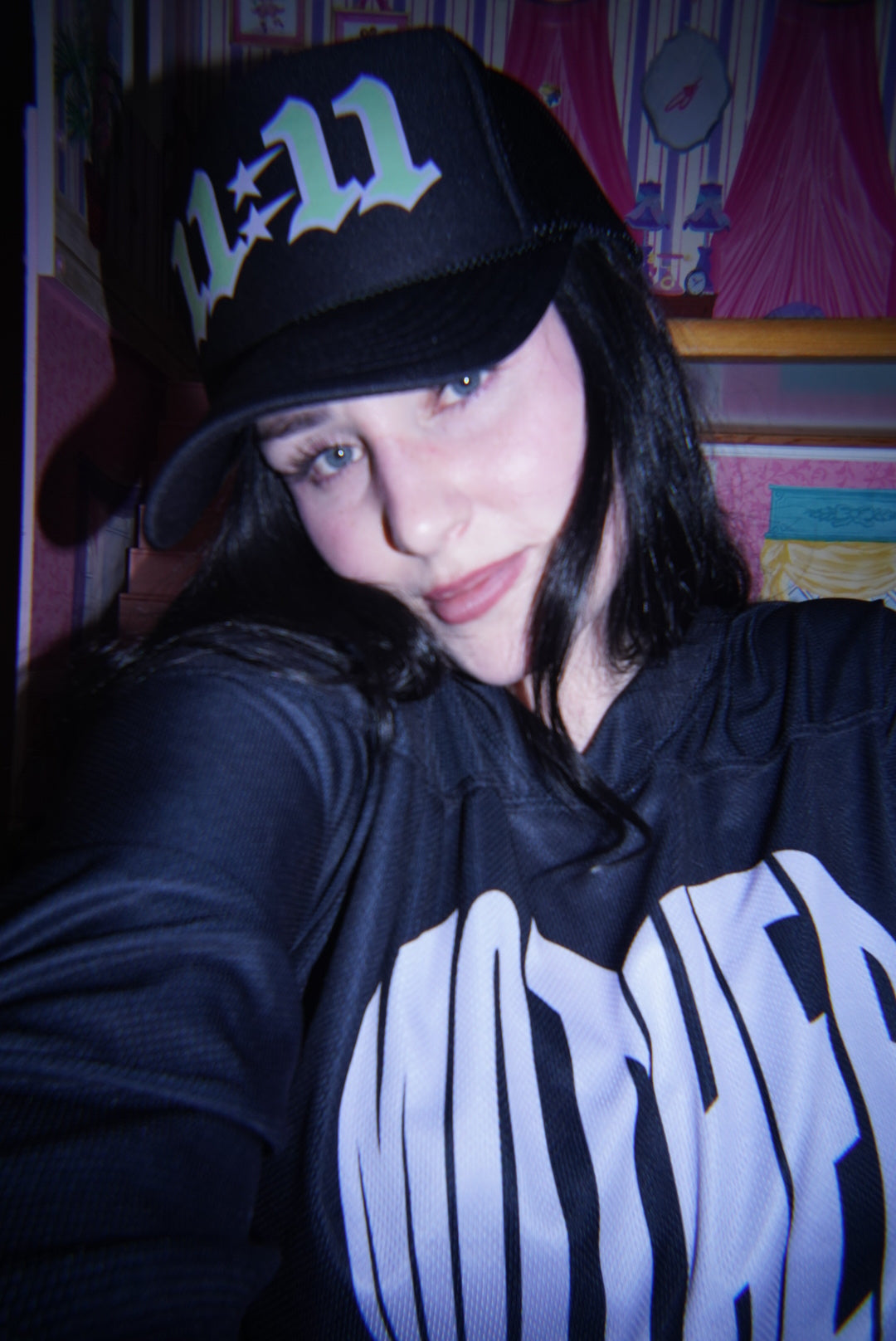 Woman wearing the LOVE WORLD 11:11 Trucker Hat in black — neon green angel number graphic, styled with MOTHER hoodie, dreamy editorial vibe