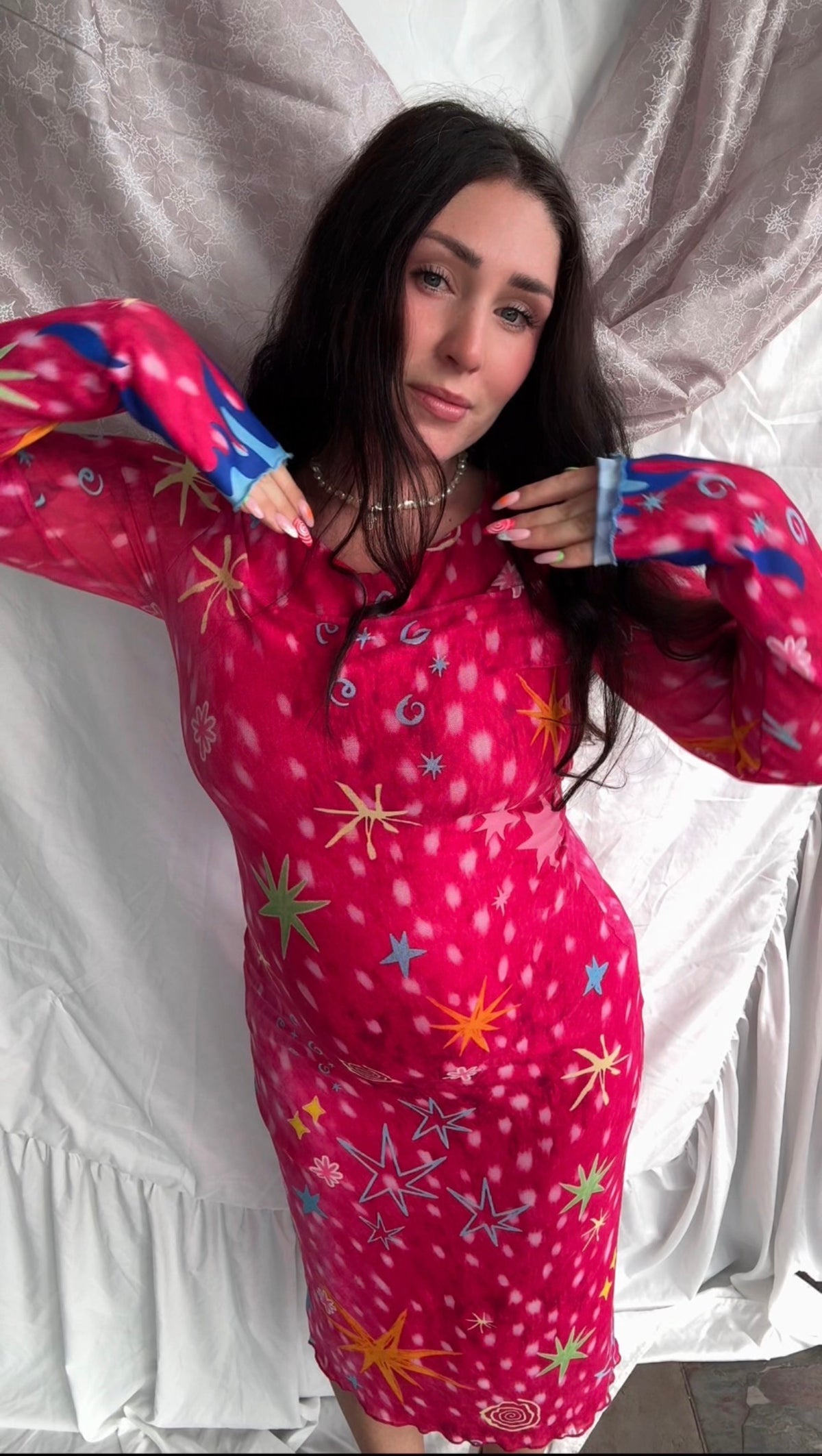 LOVE WORLD’s Deer Stars hot pink mesh midi dress with multicolored stars, spirals, and blue flame accents on long sleeves