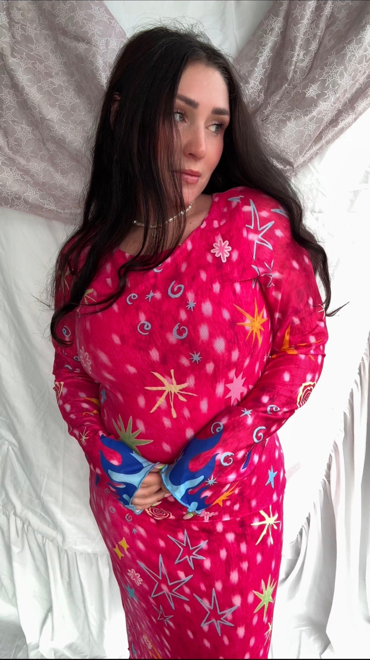 LOVE WORLD’s Deer Stars hot pink mesh midi dress with multicolored stars, spirals, and blue flame accents on long sleeves