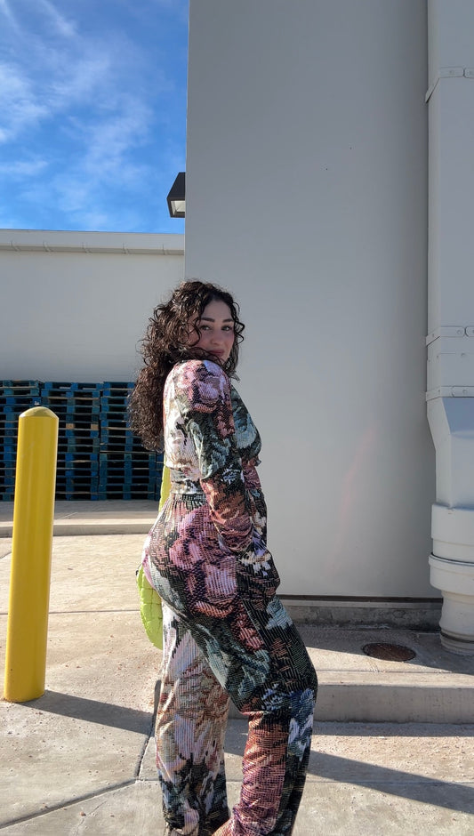 model wearing LOVE WORLD Grandma's Couch Vintage Floral Wide-Leg Pants — side view showing wide-leg silhouette and all-over tapestry floral print, styled with green mini bag, outdoor shot