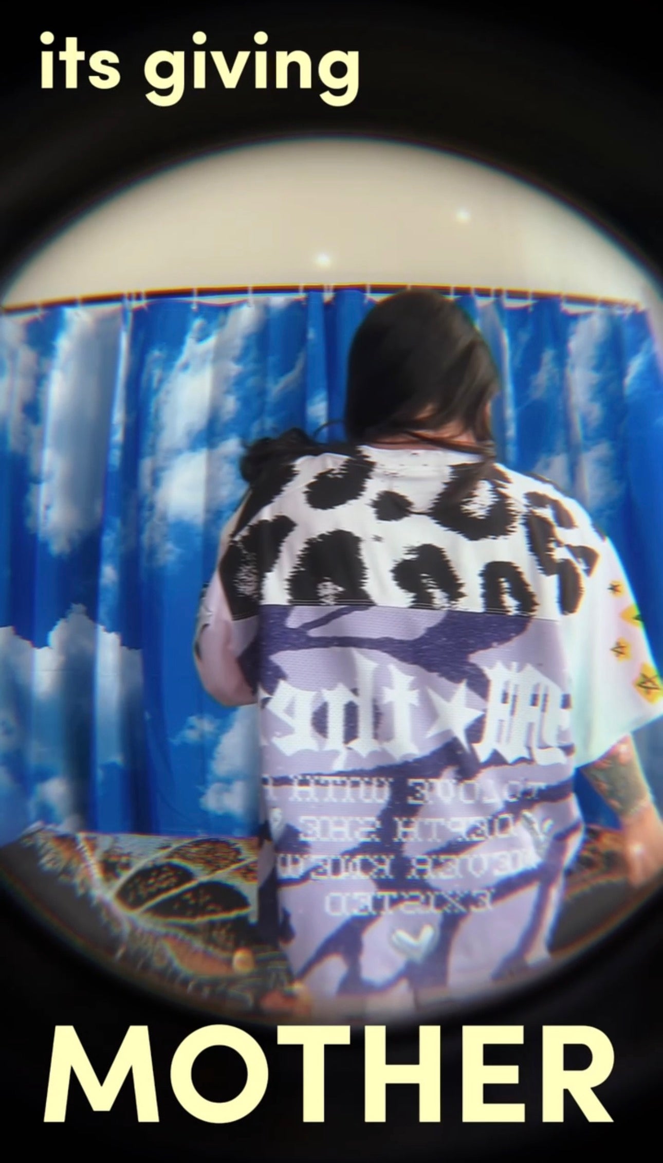 Person wearing a patterned shirt with text, standing in front of a blue curtain.womens graphic jersey, jersey for women, trendy top for women, womens clothing brand, dopamine dressing,dopamine clothing brand, t-shirt with a colorful graphic reading mother with snakeskin and leopard design, loveworldllc.com, stars and leopard jersey for women, pinterest ootd, purple womens jersey
 mental health brand, womens mental health brand